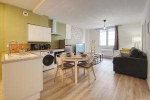 a kitchen and a living room with a table and a couch at La Balade Nîmoise Center Car Park AC in Nîmes