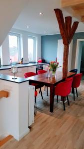 a kitchen with a wooden table and red chairs at Villa Appartements Syke in Syke