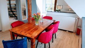 a dining room with a wooden table and red chairs at Villa Appartements Syke in Syke
