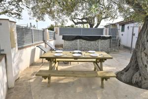 a wooden picnic table with a bench and a tree at Mas de Josep in L'Ampolla