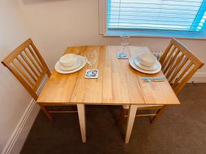 una mesa de madera con 2 sillas, platos y copas de vino en Self Contained Guest Suite 1 - Weymouth en Weymouth