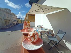 d'une table et de chaises sur un balcon avec un parasol dans l'établissement Mediterraneo Appartaments, à Lampedusa