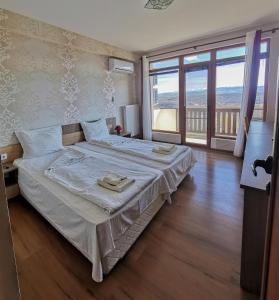 a bedroom with a large bed and a large window at Complex Magura in Rabisha