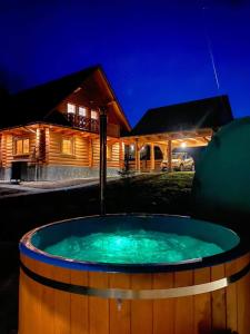 uma banheira de hidromassagem em frente a uma casa de madeira à noite em Chata Nad Potokiem w Górach em Kamesznica