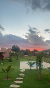 a sunset over a park with palm trees and a pathway at Paraíso Capitólio "A Pousada da Dona Perpetua" in Capitólio