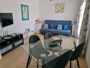 - un salon avec une table et des chaises en verre dans l'établissement Castillo Holiday Apartament- Puerta del Sol 191, à Caleta de Fuste