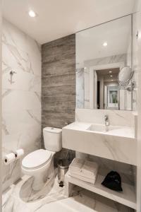 a white bathroom with a toilet and a sink at Slaviero Chapecó in Chapecó