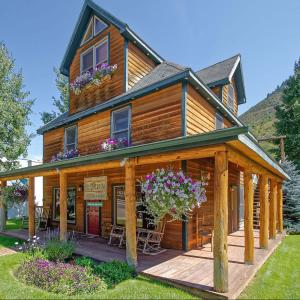 a log cabin with a porch and flowers at Minturn Inn in Minturn