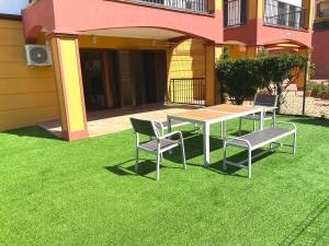 uma mesa e cadeiras num relvado em frente a uma casa em Costa Esuri Golf y Playa IV em Ayamonte