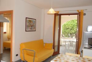 a living room with a yellow chair and a balcony at I Portici Apartments in Marina di Grosseto
