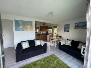 a living room with two black couches and a kitchen at 92 Lake View in Caernarfon
