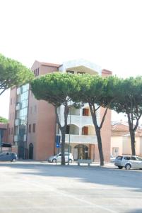 um edifício com árvores em frente a um parque de estacionamento em I Portici Apartments em Marina di Grosseto