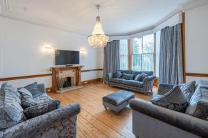 a living room with two couches and a tv at Milton Bank Garden Apartment in Broughty Ferry