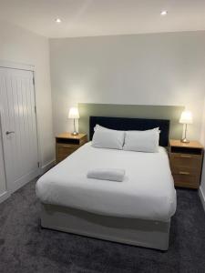 a bedroom with a large white bed with two night stands at The White City Apartment in Oban