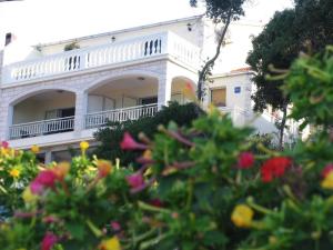 ein weißes Haus mit einem Balkon und Blumen in der Unterkunft Apartments Dijana - 20m from the sea in Prigradica