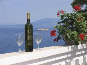 a bottle of wine and two wine glasses on a ledge at Apartments Dijana - 20m from the sea in Prigradica