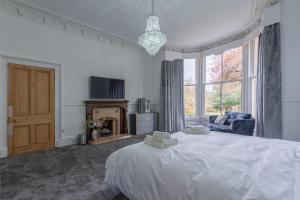 a bedroom with a white bed and a fireplace at Milton Bank Mansion Garden Apartment in Broughty Ferry