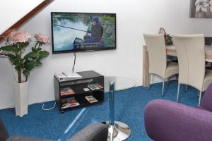 a living room with a table and a tv on the wall at Teska Bed & Breakfast in Veenendaal