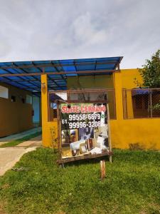 un panneau dans l'herbe devant un bâtiment jaune dans l'établissement Suites Cerrado, à Alto Paraíso de Goiás
