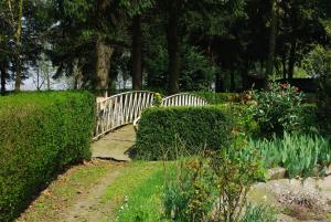 a wooden bridge in a garden with bushes and flowers at Pension Genengerhof in Viersen