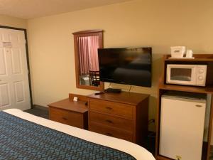 Pokój hotelowy z łóżkiem, telewizorem i kuchenką mikrofalową w obiekcie Sunset Inn - John Day w mieście John Day