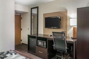 a hotel room with a desk with a chair and a television at Sleep Inn Airport in Albuquerque