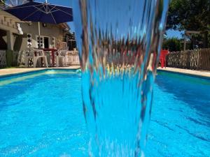 a blue swimming pool with an umbrella next to it at Pousada Nova Primavera in Ubatuba