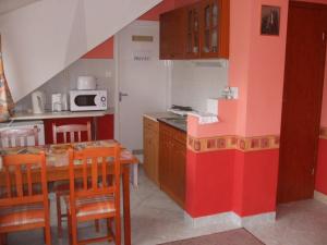a kitchen with a table and a kitchen with red and white walls at Erdős Apartments in Mosonmagyaróvár