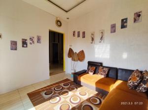 una sala de estar con sofá y algunas fotos en la pared en Puncak Pinus and Pool, en Batu