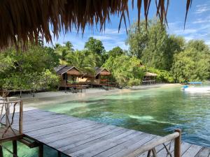 a wooden pathway leading to a resort on a beach at TABARI DIVE LODGE in Pulau Mansuar