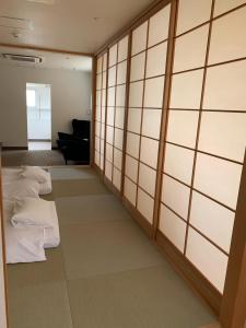 a row of beds in a room with white walls at Hotel Oxio in Okayama
