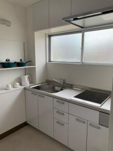 岡山的住宿－Oxio 飯店，厨房配有白色橱柜、水槽和窗户。