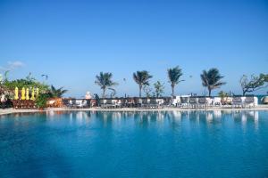 een groot zwembad van blauw water met stoelen en palmbomen bij Allezboo Beach Resort & Spa in Mũi Né