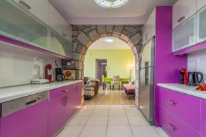 une cuisine avec des placards violets et un salon dans l'établissement Stone House Yiota, à Plaka Milou