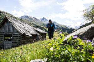 a man walking up a hill next to a hut at Hotel Alpenaussicht Obergurgl in Obergurgl