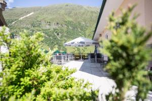 a patio with tables and chairs and an umbrella at Hotel Alpenaussicht Obergurgl in Obergurgl