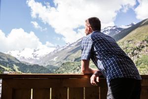 a man sitting on a fence looking at the mountains at Hotel Alpenaussicht Obergurgl in Obergurgl +54 photos