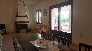 a living room with a dining room table and a window at Villa nel verde in Iglesias