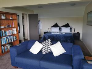 a living room with a blue couch and a bed at Breakaway at York Bay in Days Bay