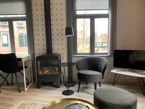 a living room with a fireplace and chairs and a television at Wetterhûske - Huisje aan de gracht in Franeker