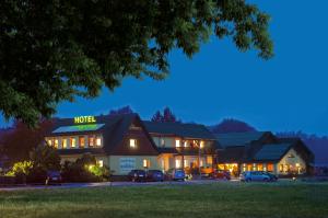 een hotel waar 's nachts auto's voor geparkeerd staan bij Familienhotel Brandtsheide in Jeserig