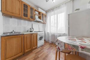 cocina con armarios de madera, fregadero y mesa en Apartment Hanaka Zeleniy 83, en Moscú