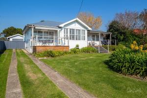 a white house with a lawn in front of it at Moruya Holiday House in Moruya