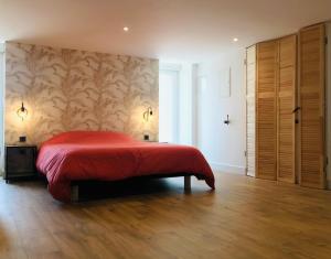 a bedroom with a red bed and a wooden floor at Le Salon de l'Isle in Carentan