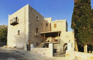 a large stone building with a balcony and a tree at Kamares Stone House 1 in Gerolimenas