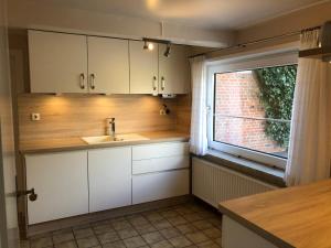 a small kitchen with a sink and a window at Großzügiges Reetdachhaus an der Nordsee in Langenhorn +24 photos