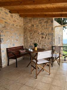 a patio with a wooden table and chairs and a table and benches at Kamares Stone House 2 in Gerolimenas