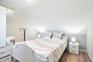 a white bedroom with a white bed and a mirror at Maison charmante à Stotzheim + jardin in Stotzheim