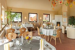 a restaurant with white tables and chairs and windows at Familienhotel Brandtsheide in Jeserig