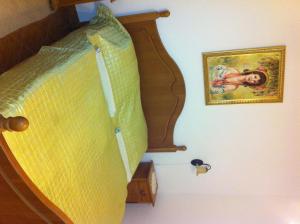 a bed with a wooden headboard and a painting on the wall at Sarokhaz Panzio in Vecsés
